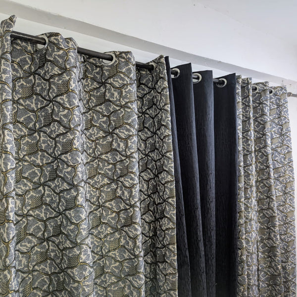 Patterned curtains with a black rod and white ceiling.
