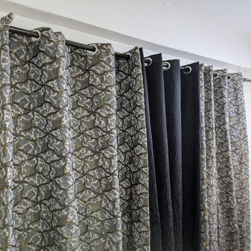 Patterned curtains with a black rod and white ceiling.