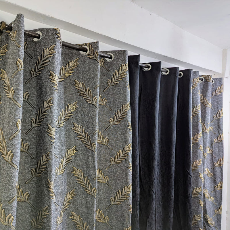 Gray curtains with gold leaf pattern hanging in a room.